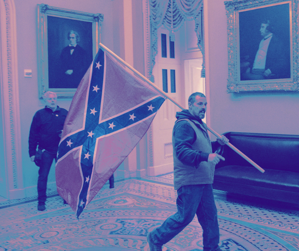 A white man carries a Confederate battle flag through a lobby inside Congress during the January 6 insurrection.