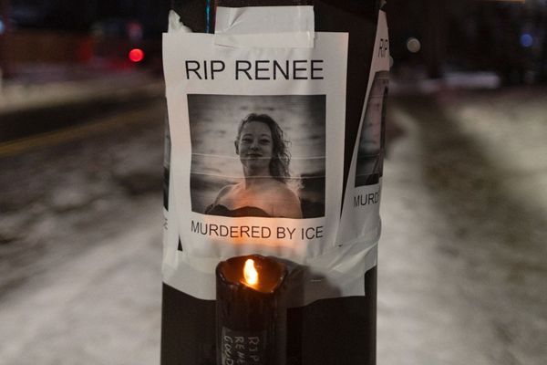 A flyer taped to a light pole shows a photo of Renee Good with the caption, "RIP Renee. Murdered by ICE." An electronic votive candle flickers below.