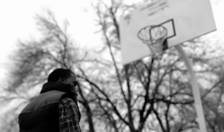 Kanye West standing on a basketball court in the "Homecoming" music video.
