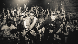 Kneecap threaten to sue industry execs urging festivals to cancel their sets, as band member charged over Hezbollah flag