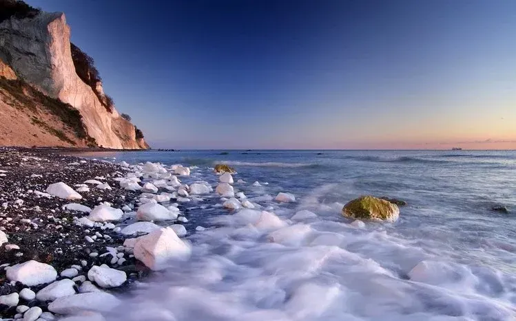 Black sand beach scenery combining dark shores, water, and snow.