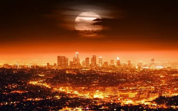 Los Angeles buildings and lights beneath a purplish sky, with yellowish tones below.