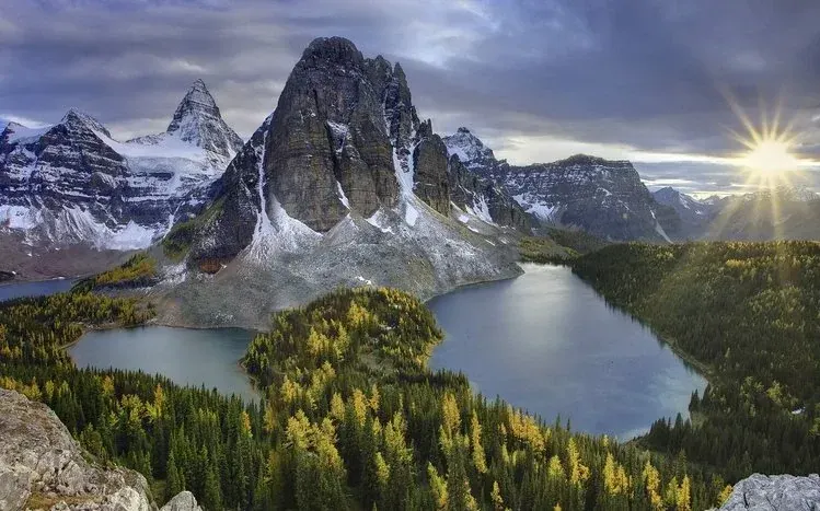 Mountain lakes reflecting trees and peaks, with starry nights and daytime clouds.