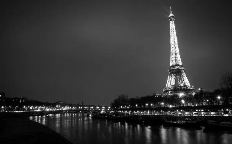 Paris wallpaper view with the Eiffel Tower at the side and city lights below.
