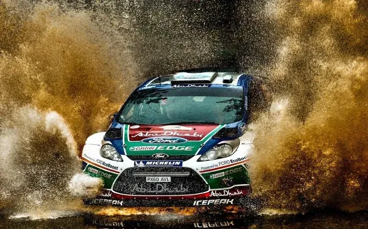 Rally cars traveling on roads and muddy passages.