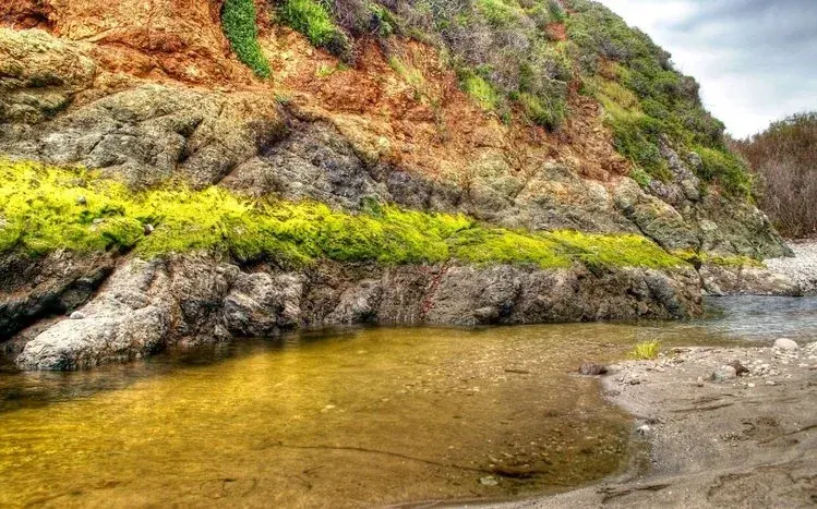 A rock beside the sea beneath a sky with related colors.