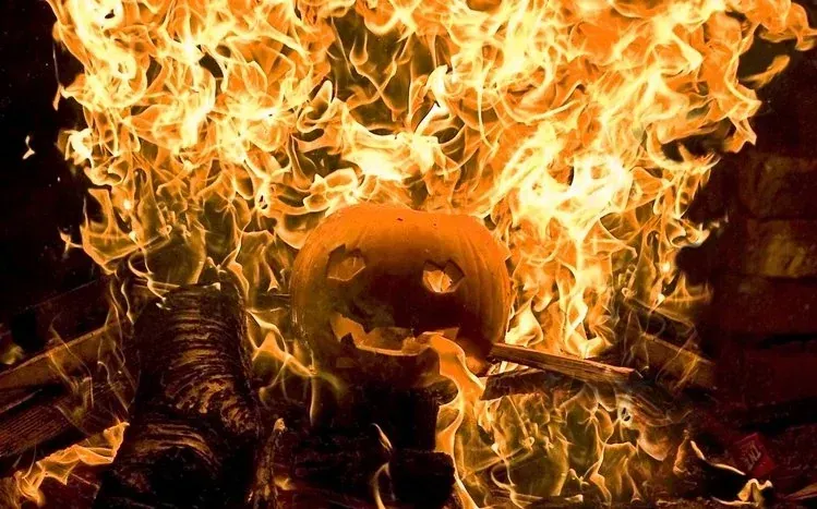 Halloween pumpkin highlighted by orange light against a black background.