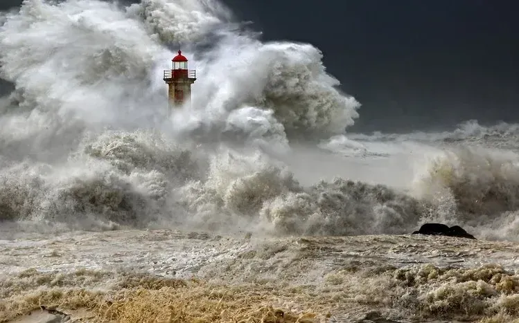 Stormy seas with high waves and spray around rocks and lighthouses.