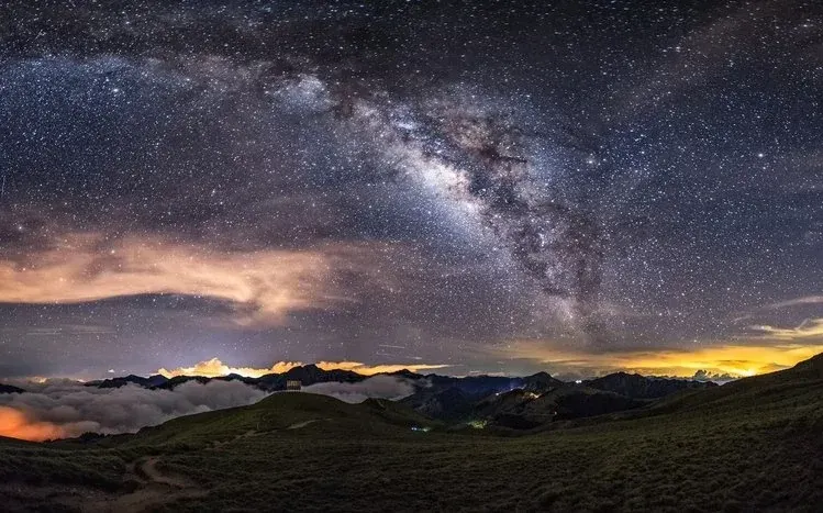 Colorful landscape foregrounds beneath starry or nebula skies in 19 wallpapers.