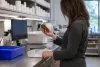 An oncology pharmacist examines an unmarked amber medication bottle in a hospital pharmacy