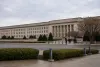 The Pentagon exterior on an overcast morning as civilian officials walk toward an entrance