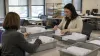 Election workers sort sealed mail-ballot envelopes at a county elections office.