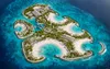 Aerial rendering of Sandy Cay showing curved white-sand beaches, turquoise coves, palm trees, and buildings across the island.