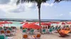 Red-and-white umbrellas shade rows of colorful lounge chairs on the sand at Hideaway Beach, overlooking turquoise water at Royal Caribbean’s private island, Perfect Day at CocoCay.