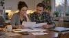 Two adults review health-insurance paperwork at their kitchen table