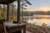 Binoculars and a folded trail map on a wooden table overlooking a quiet forested Alabama lake at sunrise