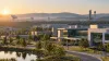 A modern aerospace and defense research campus in Huntsville at sunrise, with satellite dishes and launch infrastructure in the distance.