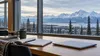 A university study table with books, a notebook and laptop overlooking a snowy Alaska mountain landscape.
