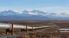 Illustrative natural-gas pipeline crossing Alaska tundra toward distant mountains.