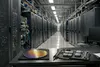Photorealistic modern data center aisle with server racks, optical fiber connections and a generic semiconductor wafer on a technician workbench, with no logos or readable text.