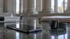A generic smartphone and smartwatch beside court papers with subtle vibration ripples reflected on a dark surface
