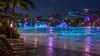 Conceptual nighttime water park scene with colorful lights reflecting across a wave pool