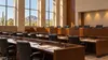 An empty legislative committee hearing room with desks, microphones and warm Arizona daylight.