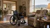 An empty wheelchair beside an armchair and caregiver supplies in a sunlit accessible Arkansas home.