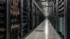 Unbranded AI data-center aisle with server racks, network cabling and liquid-cooling pipes