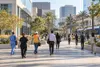 Workers in healthcare, construction, service and office attire cross a California employment district.