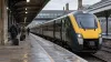 Passengers walk beside a modern intercity train at a covered British railway platform.
