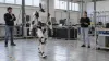 Humanoid robot undergoing mobility testing as civilian engineers observe in a robotics laboratory