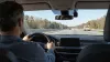 Driver on a divided highway with a generic aftermarket driver-assistance device mounted near the rearview mirror