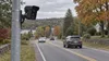 Illustrative roadside license plate reader camera overlooking cars on a New England road in autumn