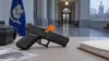 A secured generic handgun with a chamber flag on an evidence table near a blurred courthouse corridor.