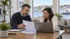 A small-business owner and employee review health-plan materials in a bright Connecticut office.
