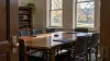 Empty university conference room with closed folders on a wooden table and an autumn campus visible through the windows.