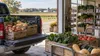 Crates of fresh produce moving from a farm pickup truck into a community food pantry