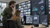 Two media product professionals review anonymous streaming analytics in a modern unbranded operations room.