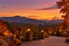 Illustrative autumn theme park walkway with glowing pumpkins and Smoky Mountain scenery at dusk