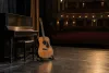 An acoustic guitar and upright piano on an empty theater stage