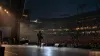 A lone guitarist performs before a stadium audience in a representative concert scene.