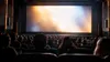 Moviegoers seated in a modern cinema auditorium facing a softly illuminated screen