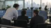 Financial risk professionals review market data on monitors in a modern trading office.