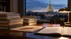 Stacks of federal budget folders on a desk with the U.S. Capitol visible at dusk
