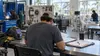 Conceptual technical-college lab with an adult student reviewing paperwork among skilled-trades and healthcare training stations