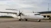 Unmarked twin-engine turboprop parked at a small regional airport in soft morning light