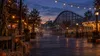 Generic autumn amusement park midway at dusk with pumpkins, string lights and a wooden roller coaster