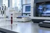 Unlabeled blood sample tube beside sequencing equipment in a modern clinical laboratory