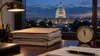 Federal budget folders and an analog clock near midnight on a desk overlooking the U.S. Capitol at dusk